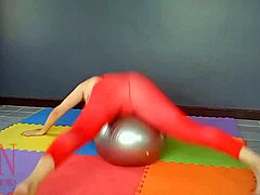 Реджина Ноар, зряла жена, практикува йога във фитнеса, докато носи червено трико, чорапогащник по йога и е бръсната